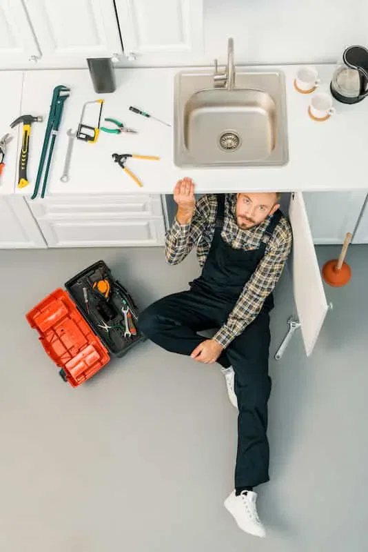 Experienced plumbing technician repairing sink demonstrating skilled service