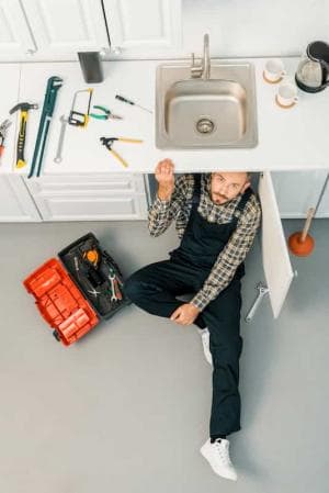 plumbing technician working under sink